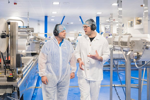 To ansatte går å snakker sammen i fabrikken